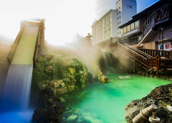 A picturesque onsen hit spring in Japan; shimmering blue waters invite you to take a dip.